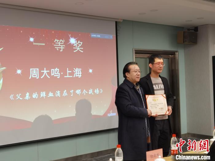 圖為作家、西北師范大學(xué)新聞與傳媒學(xué)院院長(zhǎng)徐兆壽頒發(fā)一等獎(jiǎng)證書，代領(lǐng)獎(jiǎng)?wù)呱吓_(tái)領(lǐng)獎(jiǎng)?！钅?攝